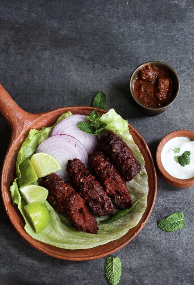 Seekh kabab served on lettuce with onions and lime